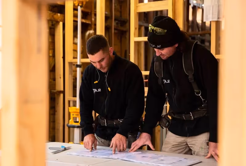 Two builders looking at plans and discussing safety and building strategy